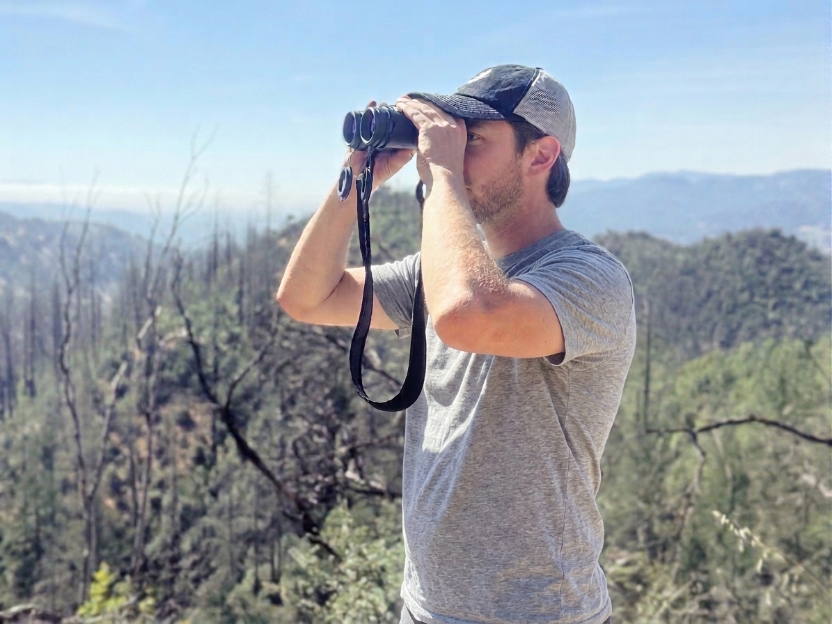 Willie glassing the hillside with binoculars above burn-scarred oak woodland in Napa Valley